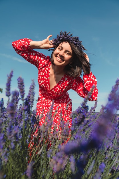 Young woman in a red dress with a wreath on her head in a lavender field