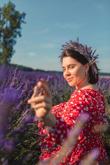 Young woman in a red dress with a wreath on her head in a lavender field