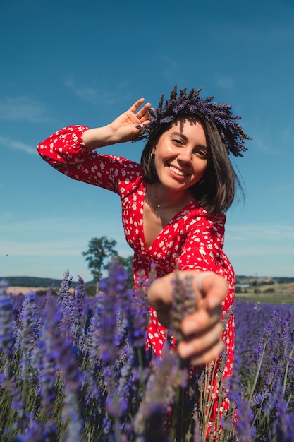 Young woman in a red dress with a wreath on her head in a lavender field