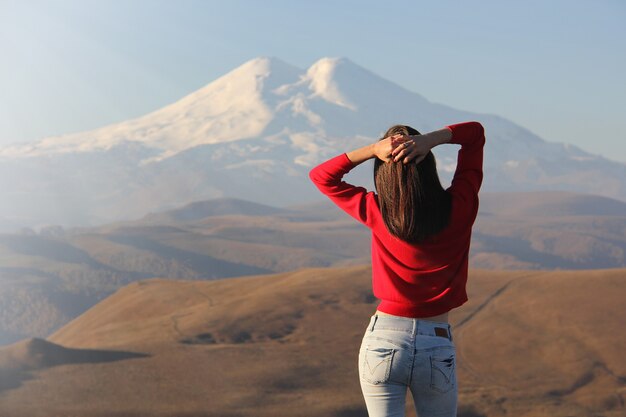 Young woman in red sweater and white jeans enjoy the sunbeams