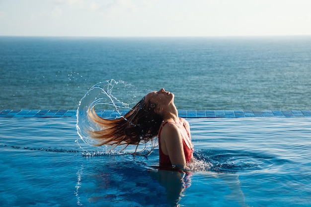 Young woman in red swimsuit tossing hair out of the water