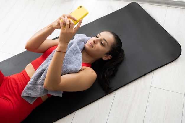 Young woman in red tracksuit doing exercise or yoga at home