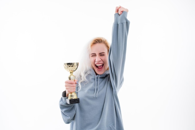 A young woman rejoices at winning the competition Model with the cup of the winner of the competition on a white background