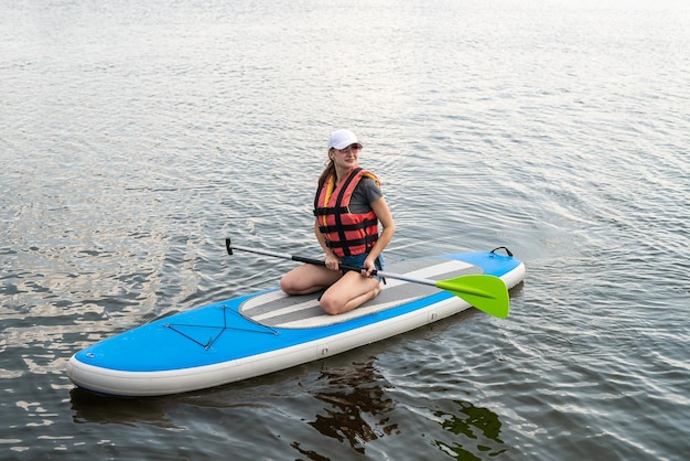 Young woman relax on SUP Stand up paddle board in summer time