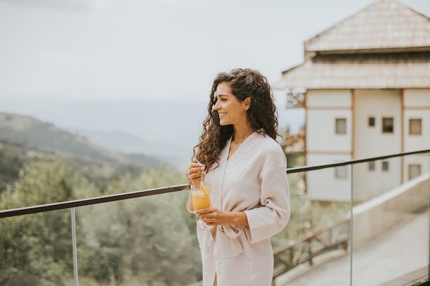 Young woman relaxing and drinking fresh orange juice on the outdoor terrace