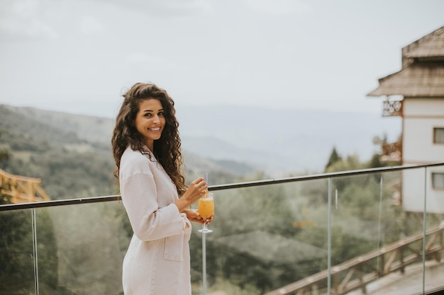 Young woman relaxing and drinking fresh orange juice on the outdoor terrace