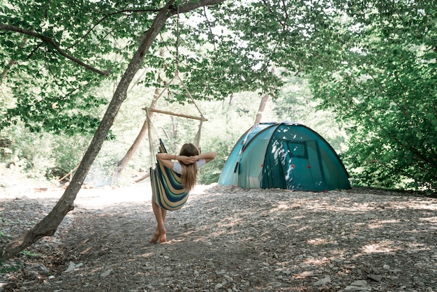 A young woman relaxing in a hammock in a wood.