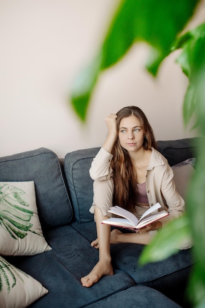 Young woman relaxing on the sofa and reading a book