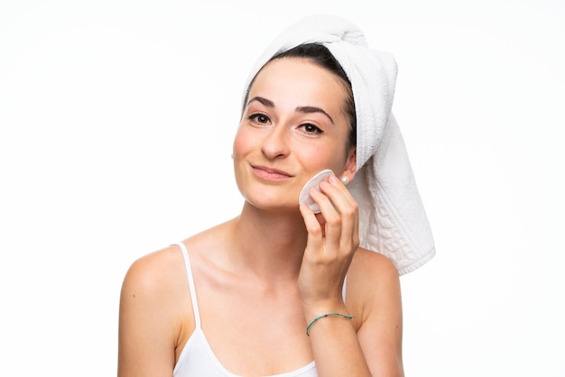 Young woman removing makeup from her face with cotton pad