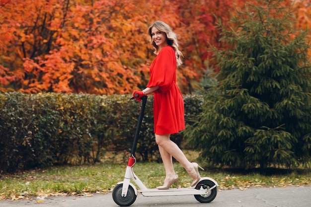 Young woman riding electric scooter in autumn city