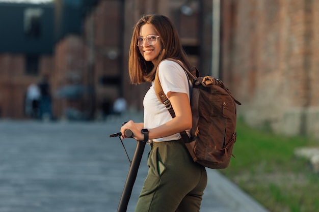 Young woman riding electric scooter in city urban street