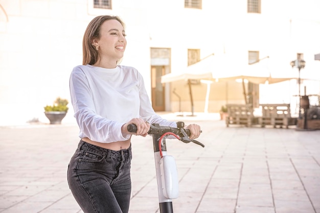 Young woman riding an electric scooter little village background