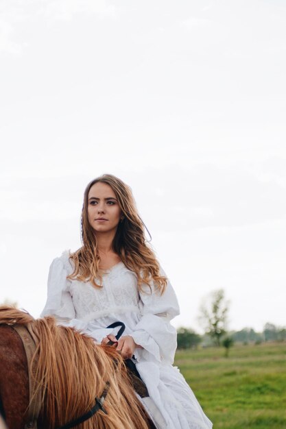 Photo young woman riding horse on field