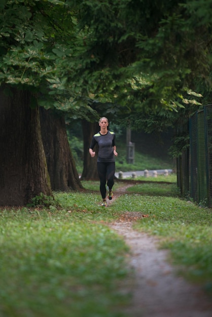 Young Woman Running In Wooded Forest Area - Training And Exercising For Trail Run Marathon Endurance - Fitness Healthy Lifestyle Concept