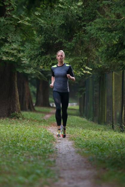 Young Woman Running In Wooded Forest Area - Training And Exercising For Trail Run Marathon Endurance - Fitness Healthy Lifestyle Concept