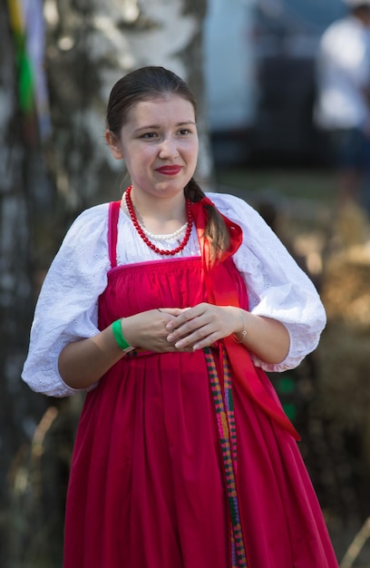 Young woman in russian folk bright scarlet dress for slavic holiday