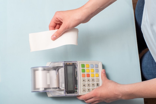 A young woman's hands tearing a check from a cash register after purchasing a product