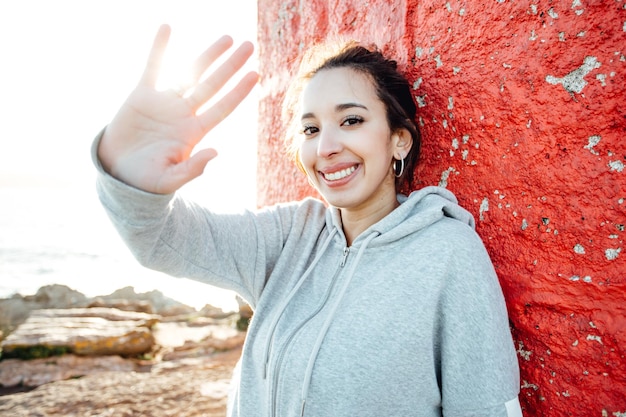 Young woman saluting to camera resting while traveling summer sunny day holiday and vacation concept Light beam and motion concept Happy and vibrant life portrait Traveling alone woman concept