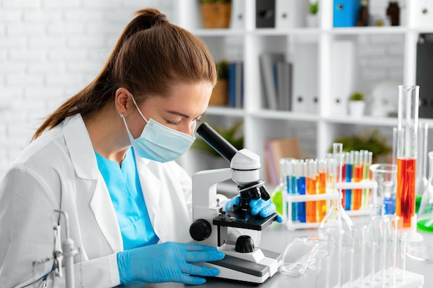 Young woman scientist using microscope in laboratory close up