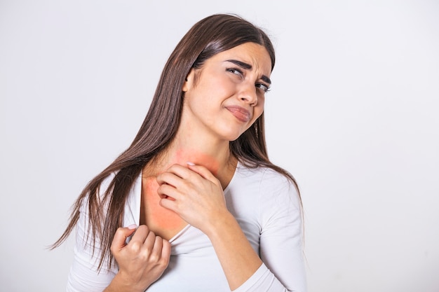 Young woman scratching her neck due to itching on a gray background. Female has an itching neck. The concept of allergy symptoms and healthcare