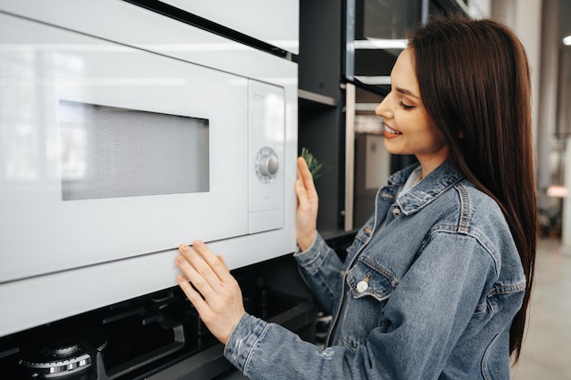 Young woman selected a new microwave oven in hypermarket