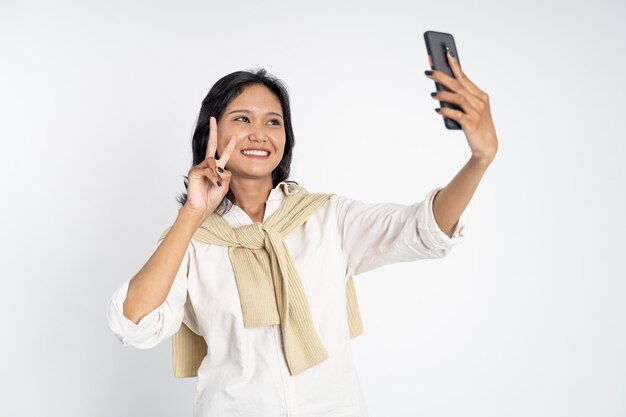 Young woman selfie using mobile phone camera with v sign