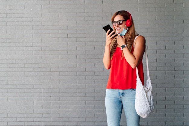 Young woman sending a voice message with her cell phone on. Concept of new normality and fight against the virus.