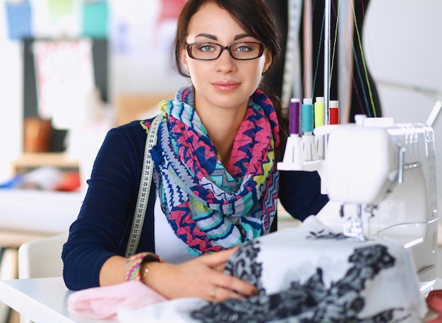 Young woman sewing while sitting at her working place