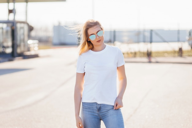 Young woman in shirt and jeans posing outdoors