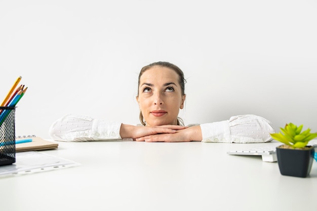 Young woman in a shirt looks up peeking out from behind the workplace