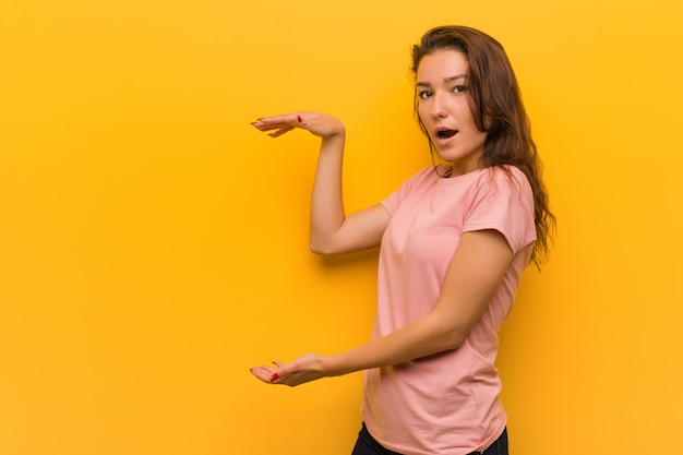 Young woman shocked and amazed holding something between her hands