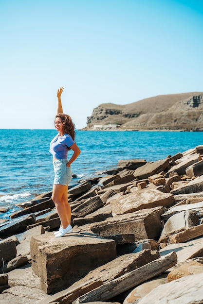 A young woman in shorts on a rocky beach made of natural stones in the Crimea