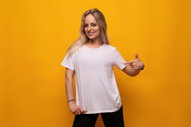 Young woman showing on blank mockup white tshirt on orange background