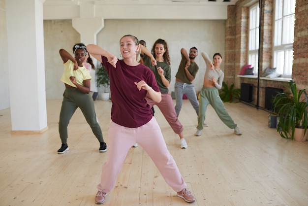 Photo young woman showing dance exercises to the people during classes in gym