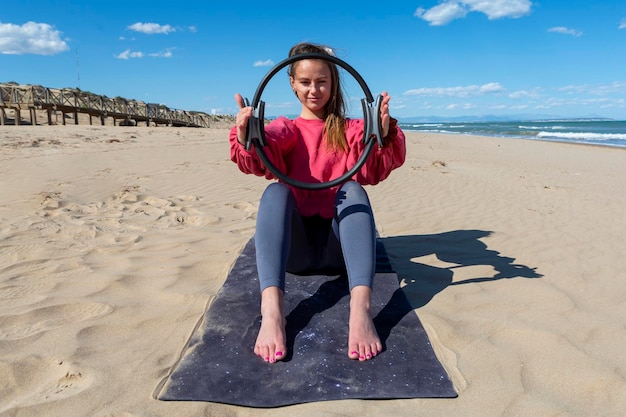 Young woman showing pilates hoop on the beach