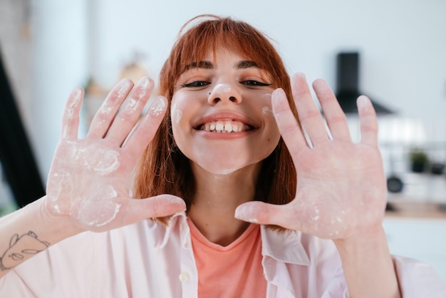 Young woman shows her hands in flour in the kitchen