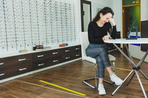 A young woman sits and chooses glasses in an ophthalmology salon Bad eyesight