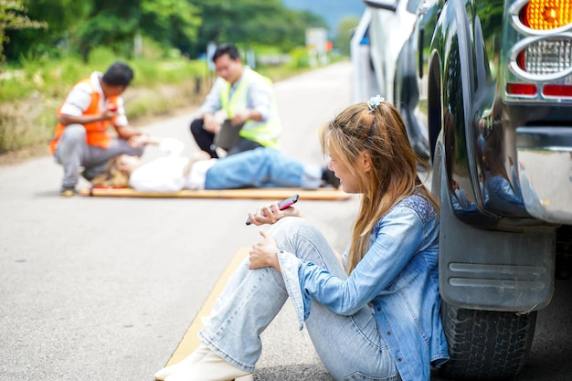 A young woman sits crying next to the car she crashed into someone on the road