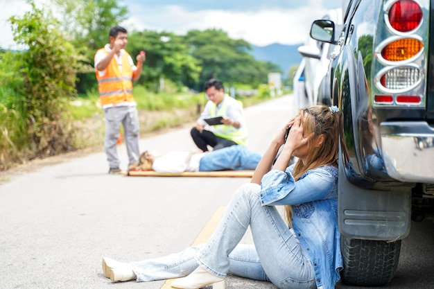 A young woman sits crying next to the car she crashed into someone on the road