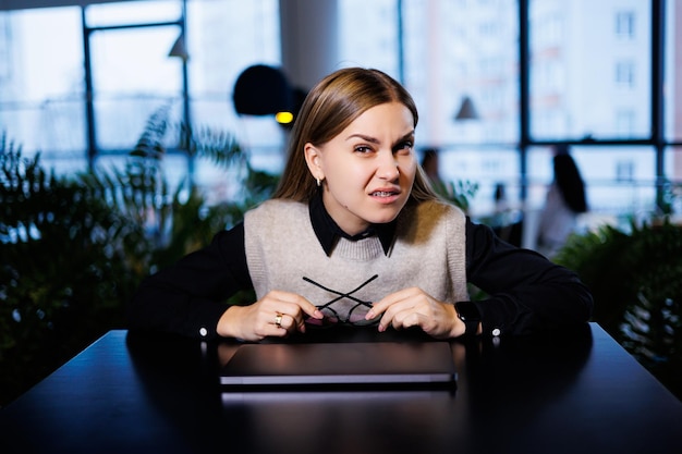 A young woman sits at a table with a closed laptop after work Woman working remotely