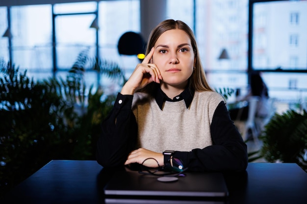 A young woman sits at a table with a closed laptop after work Woman working remotely