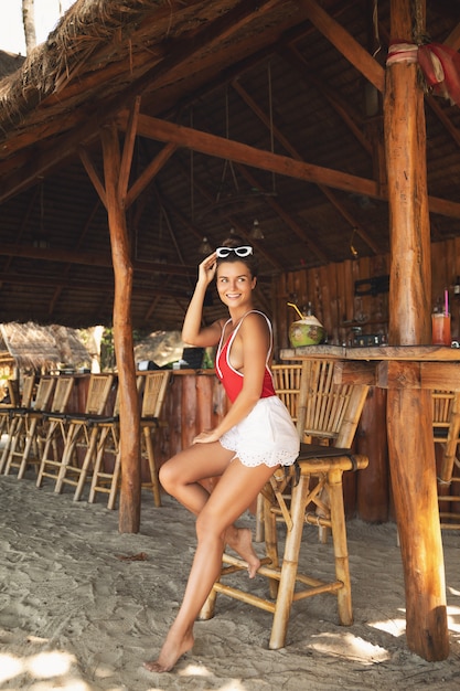 Young and woman sitting in authentic beach bar with a coconut drink