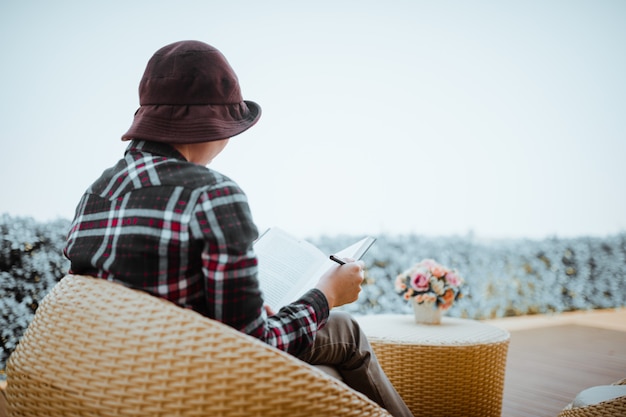 Young woman sitting in backyard, reading book and relaxing. Blurred background.Horizontal, film effect.