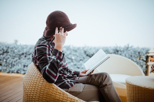 Young woman sitting in backyard, reading book and relaxing. Blurred background.Horizontal, film effect.