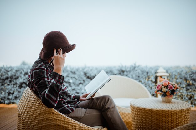 Photo young woman sitting in backyard, reading book and relaxing. blurred background.horizontal, film effect.