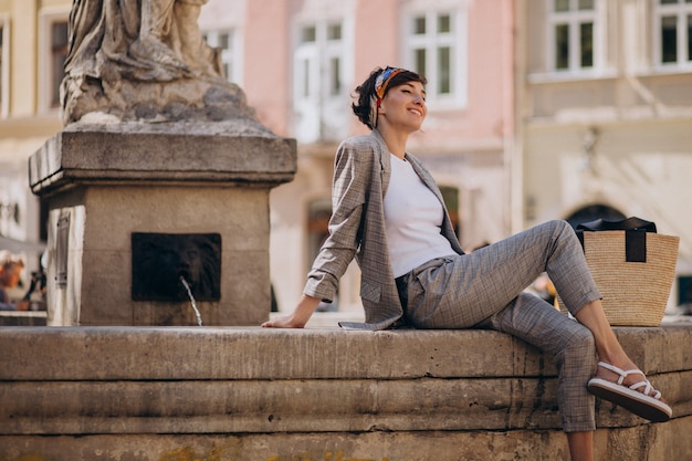 Young woman sitting by the fountain