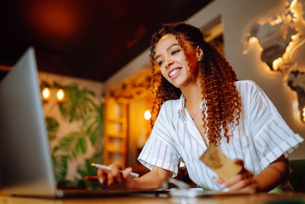 Young woman sitting at cafe making online shopping using credit card and laptop Online shopping