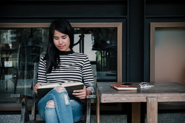 Young woman sitting on chair in cafe relaxing reading book.