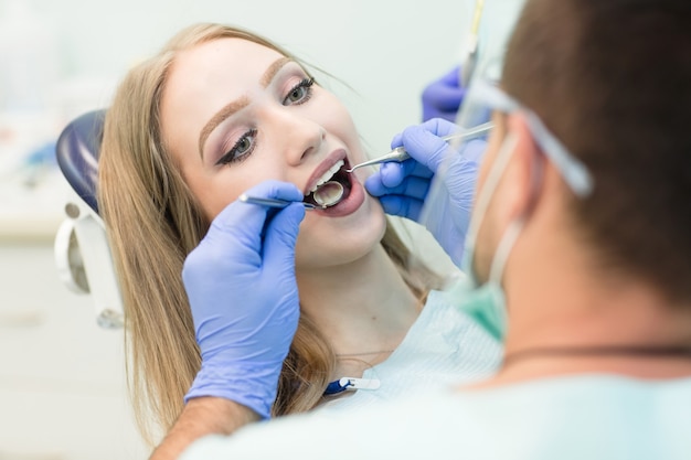 young woman sitting in the dentist's chair with opened mouth at dentist's office while having examination.