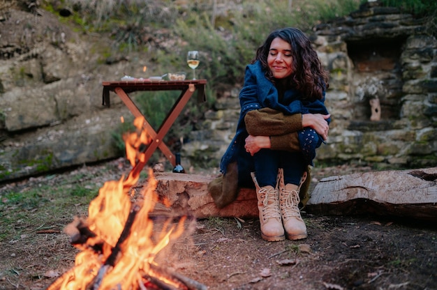 Young woman sitting next to a fire during a winter picnic.